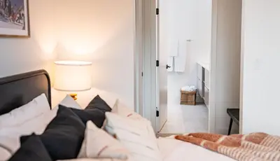 a bedroom with a bed with white sheets and pillows at The Monashee House by Revelstoke Vacations in Revelstoke