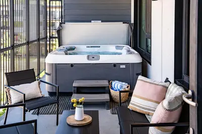 a hot tub on a balcony with chairs and a table at The Selkirk House by Revelstoke Vacations in Revelstoke