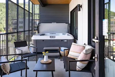 a patio with a grill and chairs on a balcony at The Selkirk House by Revelstoke Vacations in Revelstoke