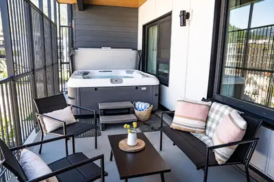 a screened in porch with a hot tub and chairs at The Selkirk House by Revelstoke Vacations in Revelstoke