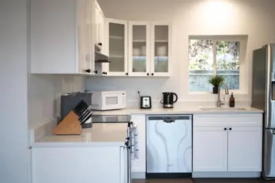 a white kitchen with white cabinets and a microwave at Private Mountainside Home in Chilliwack