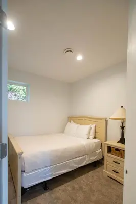 a bedroom with a bed and a lamp and a window at Private Mountainside Home in Chilliwack