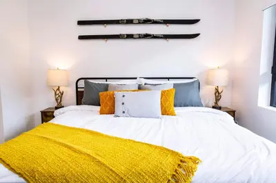 a bedroom with a bed with a yellow blanket at Revy's Stellar Retreat in Revelstoke