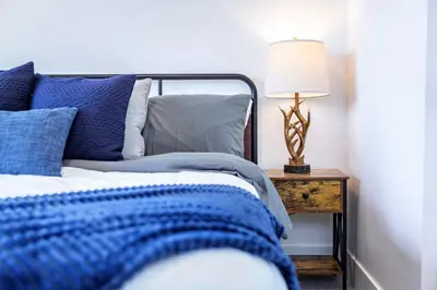 a bed with blue pillows and a lamp on a night stand at Revy's Stellar Retreat in Revelstoke