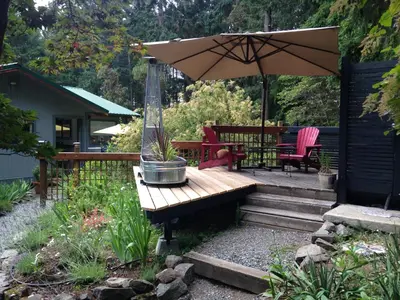a patio with a wooden bench and an umbrella at Salt Spring Carriage House B&B in Ganges