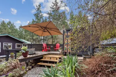 a patio with two chairs and an umbrella at Salt Spring Carriage House B&B in Ganges
