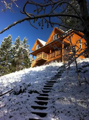 a log cabin in the snow with stairs leading to it at Canmore Alpine Hostel - Alpine Club of Canada in Canmore