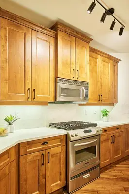 a kitchen with wooden cabinets and a stove top oven at Lakeside Luxe Haven in West Kelowna