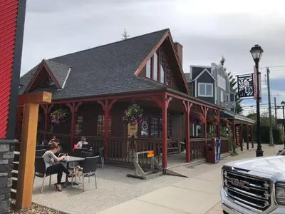 a woman sitting at a table in front of a building at Rocky Mountain View Bed & Breakfast in Cochrane
