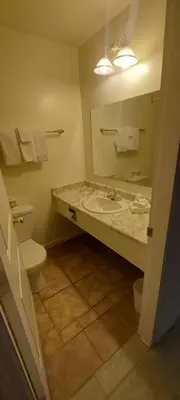 a bathroom with a sink and a toilet and a mirror at Granby River Inn & Suites in Grand Forks