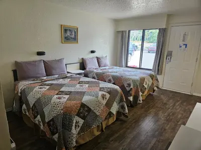 two beds in a room with a window at Granby River Inn & Suites in Grand Forks