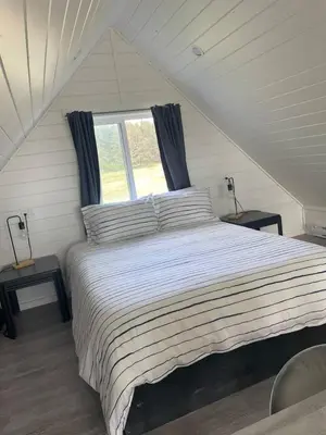 a bedroom with a large bed with a window at Sunrise Cabin- The Loft - secluded Beach front guest house in Sandspit