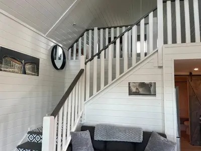 a staircase with a couch and a clock on the wall at Sunrise Cabin- The Loft - secluded Beach front guest house in Sandspit