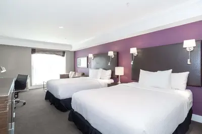 two beds in a hotel room with purple walls at Sandman Signature Kamloops Hotel in Kamloops