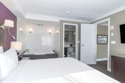 a bedroom with a white bed and a bath tub at Sandman Signature Kamloops Hotel in Kamloops