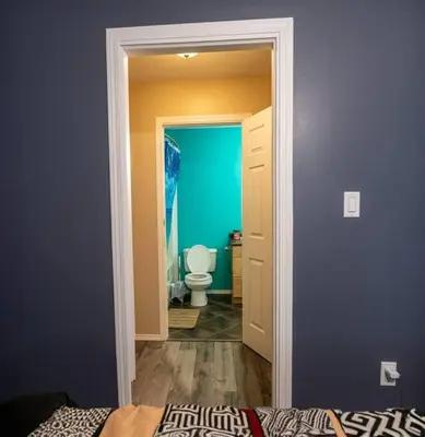 a bathroom with a toilet and a blue wall at Pink door-ed wonder in Grande Prairie