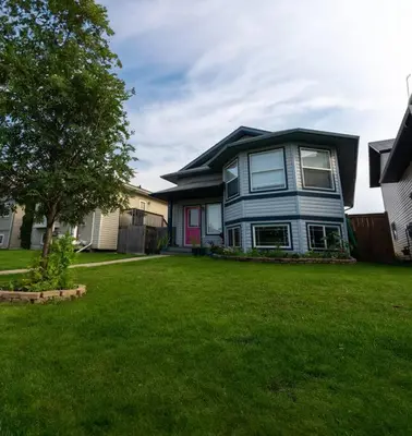 a blue house on a lawn in a yard at Pink door-ed wonder in Grande Prairie