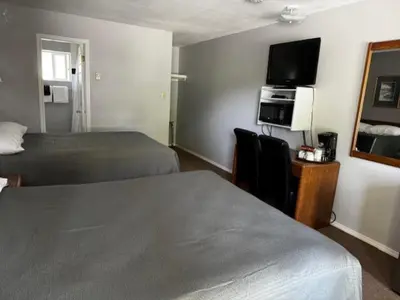 a hotel room with two beds and a flat screen tv at Clearwater Country Inn in Clearwater