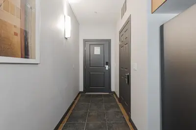 a hallway with a black door and a tile floor at Premier Residence - Fort McMurray in Fort McMurray