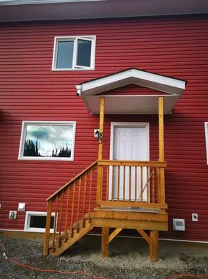 a red house with a wooden porch on it at Comfort First - sleeps 6 in Whitehorse