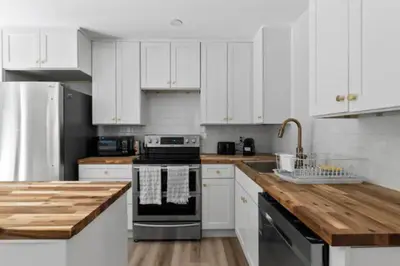 a kitchen with white cabinets and a wooden counter top at Mid-Century Modern Dream Retreat in West Kelowna