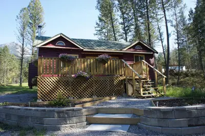 a log cabin with a porch and stairs to it at Fairmont Mountain Bungalows in Fairmont Hot Springs