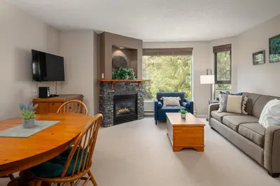 a living room with a table and a fireplace at 1BR in Marquise, Close to Ski Hill, Pool, Sauna, Hot Tub, Fitness Suite, Fireplace in Whistler