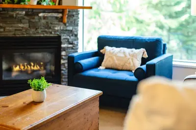 a living room with a blue couch and a fireplace at 1BR in Marquise, Close to Ski Hill, Pool, Sauna, Hot Tub, Fitness Suite, Fireplace in Whistler