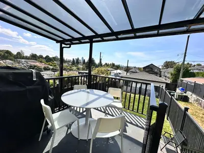 a patio with a table and chairs on a balcony at Modern and New house near PNE with Big Garden and Free Parking in Vancouver