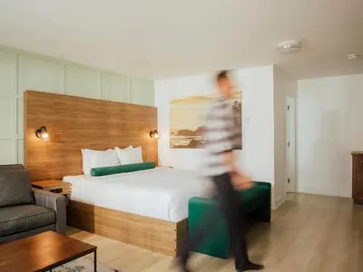 a person in a hotel room with a bed and a couch at Ucluelet Wildwood Inn in Ucluelet