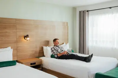 a man sitting on a bed in a hotel room at Ucluelet Wildwood Inn in Ucluelet