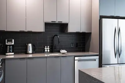 a kitchen with white cabinets and a stainless steel refrigerator at Rummy's Adventure Bay by Revelstoke Vacations in Revelstoke