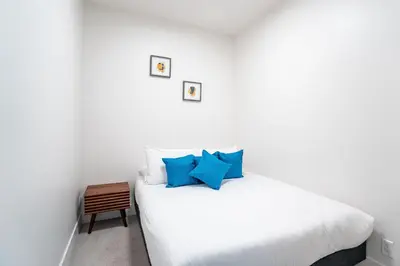 a bedroom with a white bed with blue pillows at Rummy's Adventure Bay by Revelstoke Vacations in Revelstoke