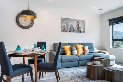 a living room with a blue couch and a table at Rummy's Adventure Bay by Revelstoke Vacations in Revelstoke