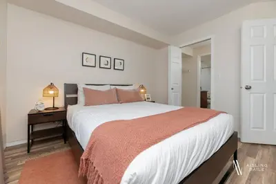 a bedroom with a large bed and a table with a night stand at Light N Airy, Pool, Hot Tub, Pets, Ground Floor in Invermere