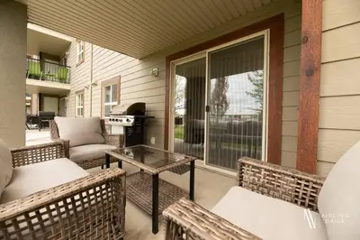 a screened porch with chairs and a table and a grill at Light N Airy, Pool, Hot Tub, Pets, Ground Floor in Invermere