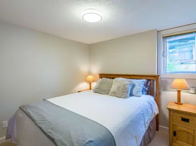 a bedroom with a bed with two lamps and a window at The Alpine I No Service Fee's I Ski-in Ski-Out I in Silver Star