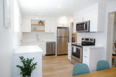 a kitchen with white cabinets and stainless steel appliances at Surfs Inn Guesthouse & Cottages in Ucluelet