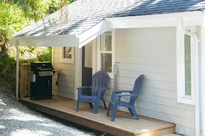 two blue chairs sitting on the porch of a house at Surfs Inn Guesthouse & Cottages in Ucluelet
