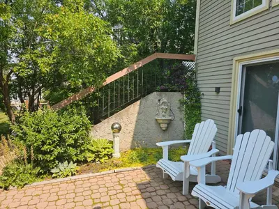 two white chairs sitting on a patio in front of a house at Window Hill in St. Albert