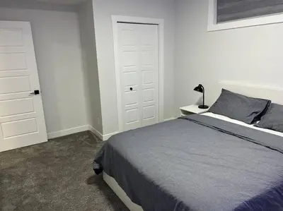 a bedroom with a bed and a white door at Modern Luxury Private Suite in Airdrie