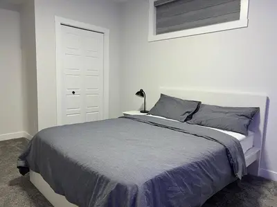 a bedroom with a bed and a white door at Modern Luxury Private Suite in Airdrie