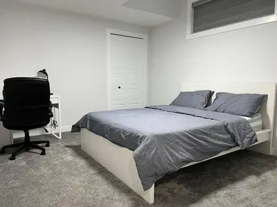 a bedroom with a bed and a desk and a chair at Modern Luxury Private Suite in Airdrie