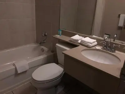 a bathroom with a sink and a toilet and a bath tub at Travellers Inn in Calgary