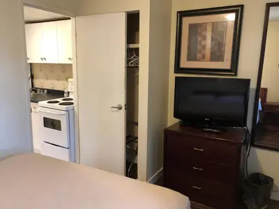 a bedroom with a television on a dresser with a kitchen at Travellers Inn in Calgary