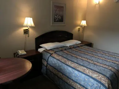 a hotel room with a bed and a table and two lamps at Travellers Inn in Calgary