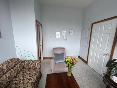 a living room with a couch and a vase of flowers on a table at Charming Hidden Gem- Ocean View and Marina in Campbell River