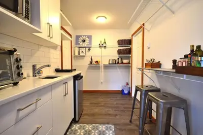 a kitchen with white cabinets and two stools in it at Charming Hidden Gem- Ocean View and Marina in Campbell River