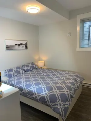 a bedroom with a bed with a blue comforter at Entire 2BR Guest House in Quiet Area in Nanaimo