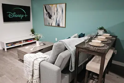 a living room with a table with a chair and a couch at Beautiful Suite King Bed,Long Stays,Disney,Airport in Edmonton